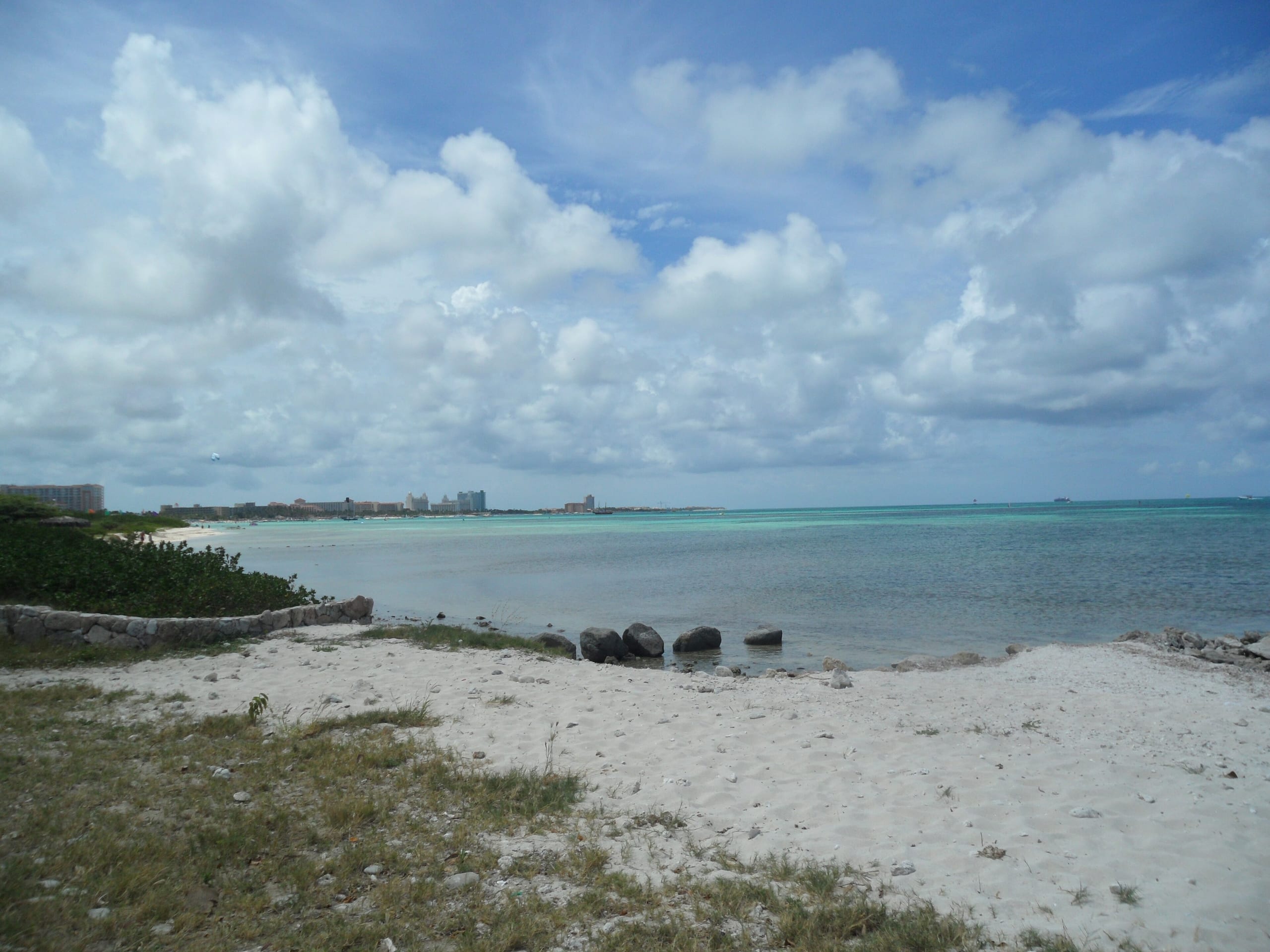 The Palm Beach high-rise hotels on the horizon across turquoise shallows, seen from the sand at Hadicurari Beach, Aruba