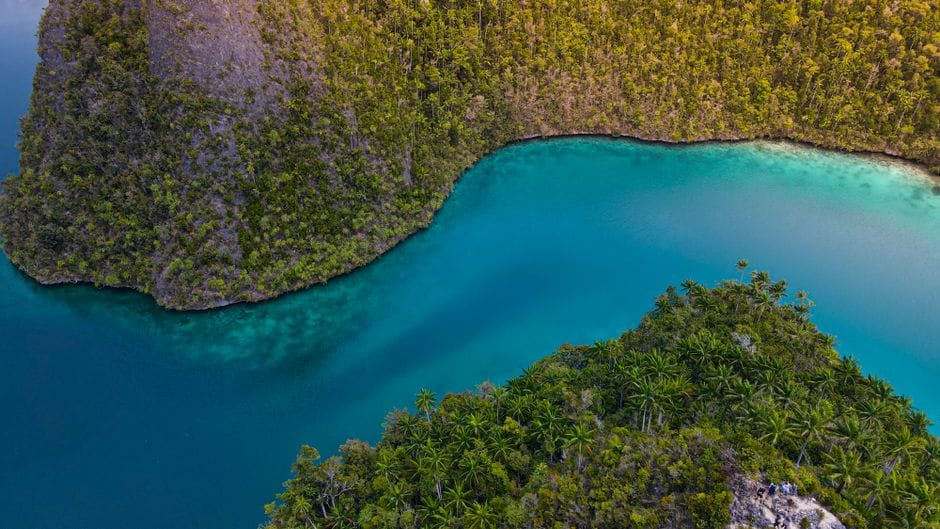 A turquoise lagoon curving around a green island at Ao Nang in Krabi, Thailand, seen from above