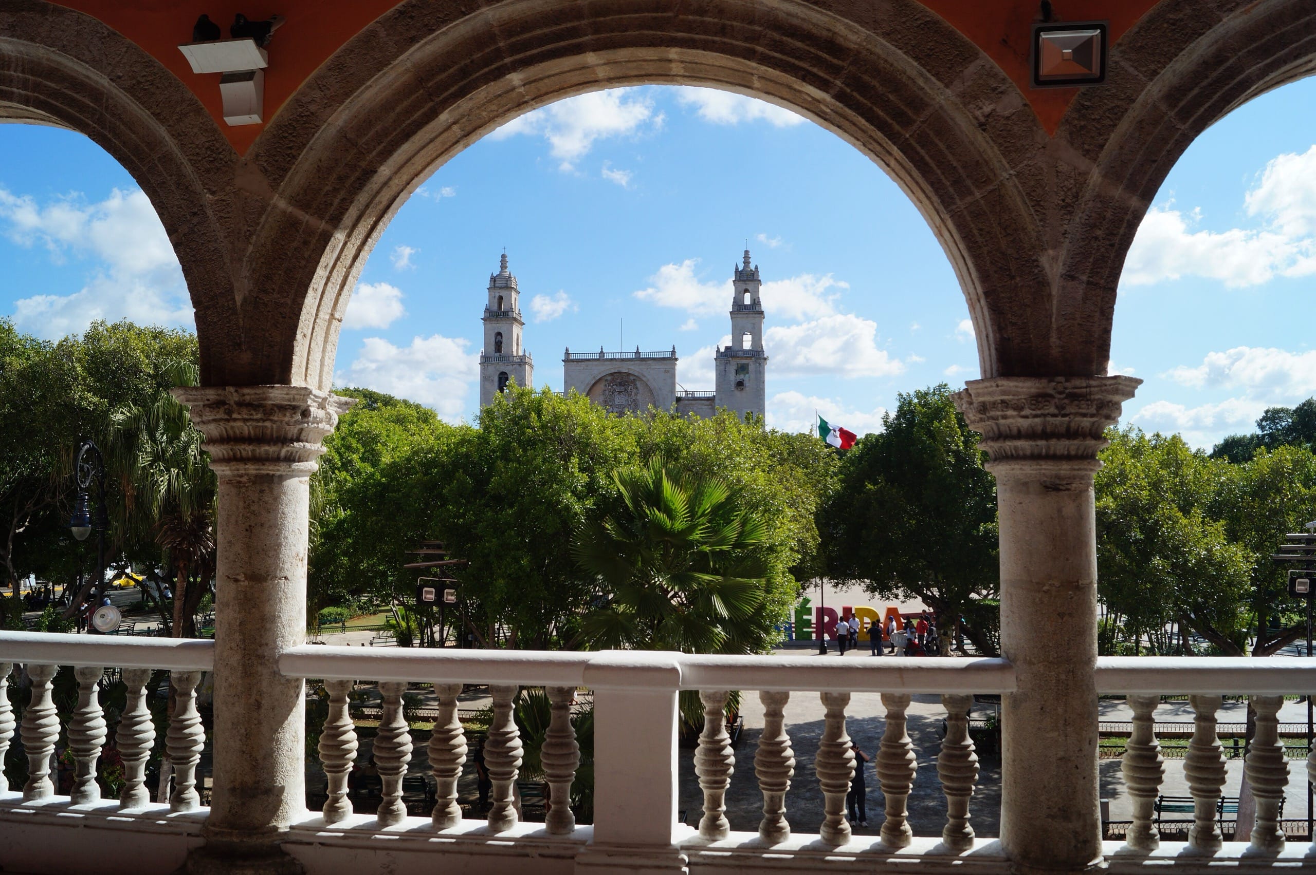 Twin church towers framed by stone arches above the Plaza Grande in Mérida