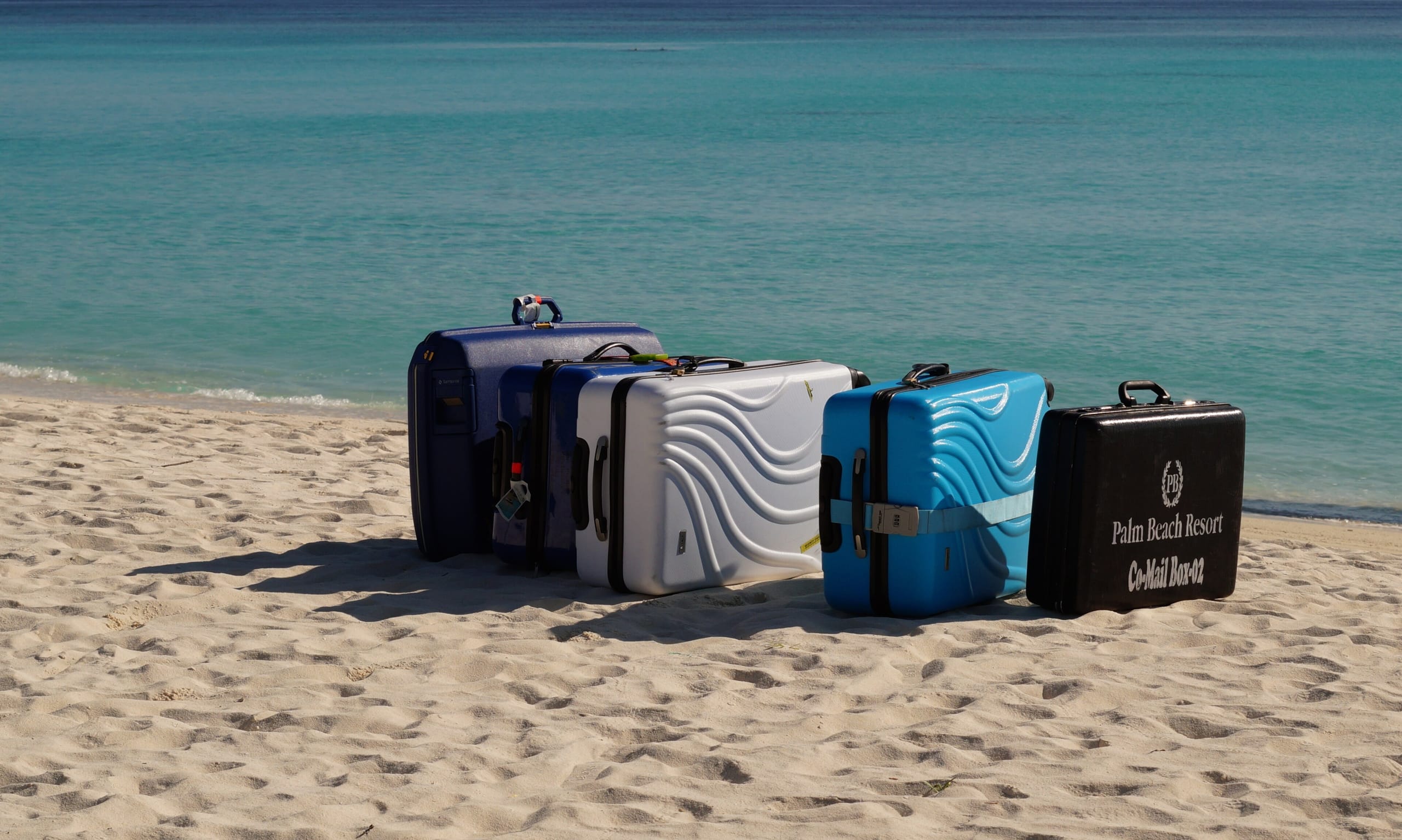 Suitcases lined up on the sand at Madhiriguraidhoo, Lhaviyani Atoll, waiting for the seaplane