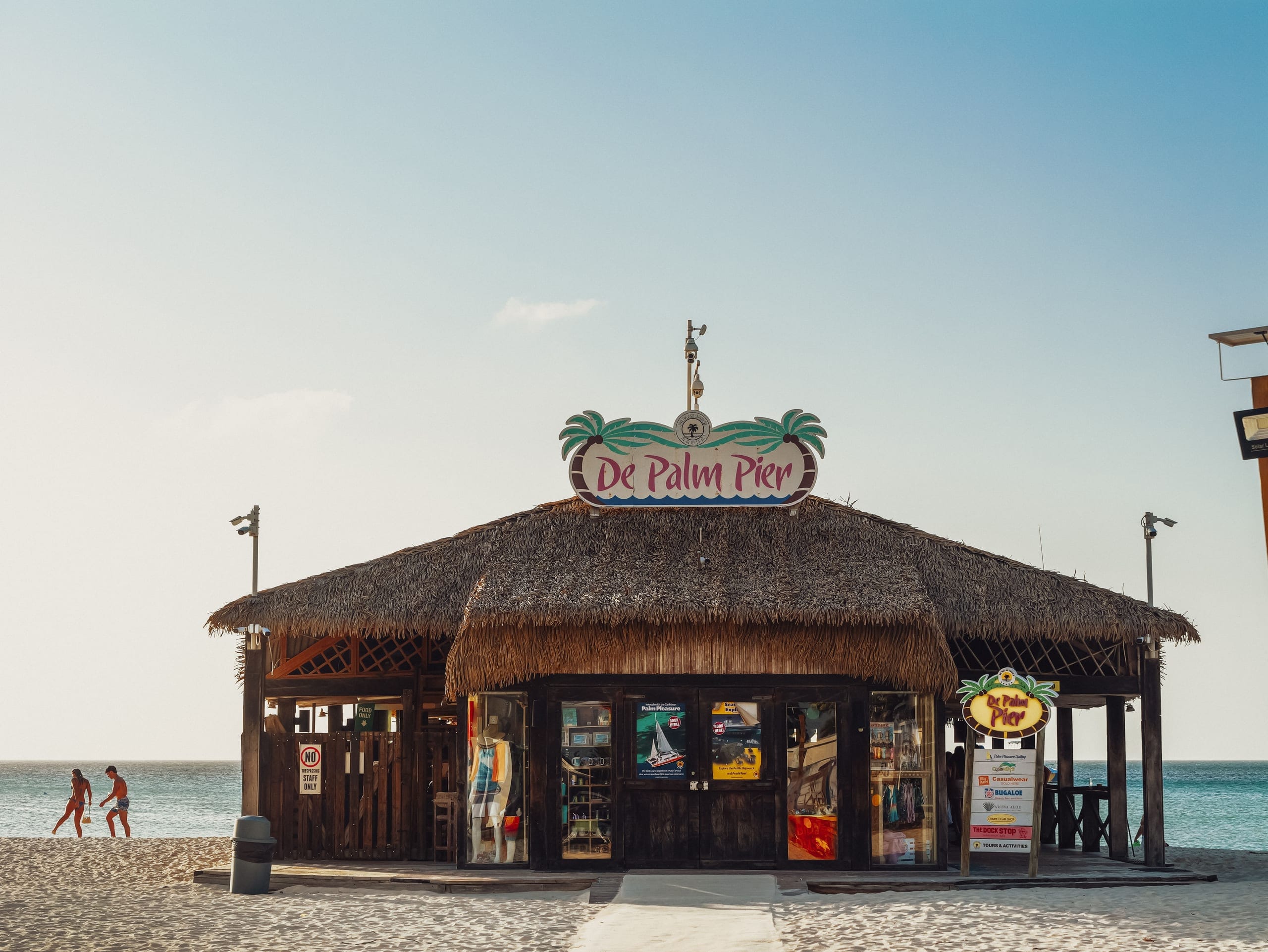 The thatched De Palm Pier kiosk standing on the sand with its sign up