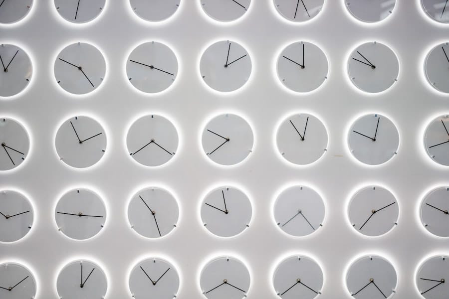 A wall of identical backlit clocks, each showing a different time